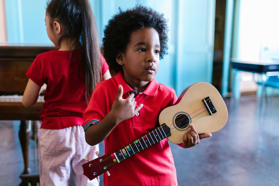 Little boy in red polo shirt holding a small guitar