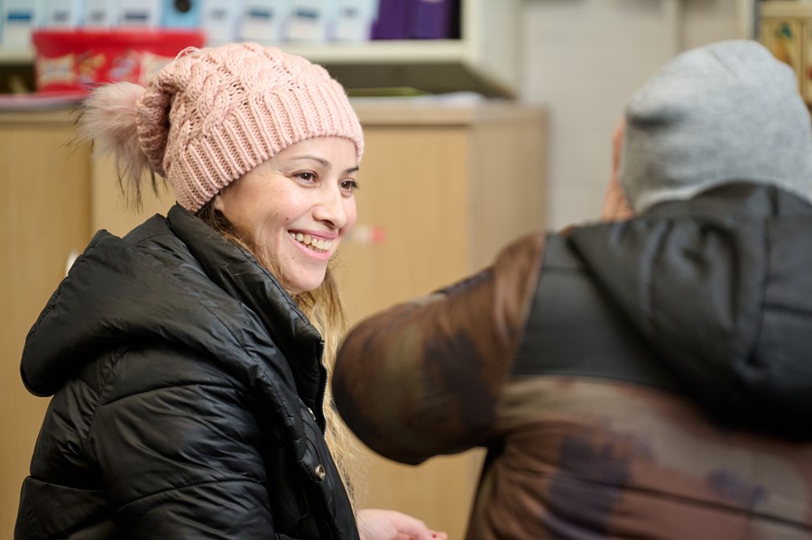 Lady in pink woollen hat smiling at another person