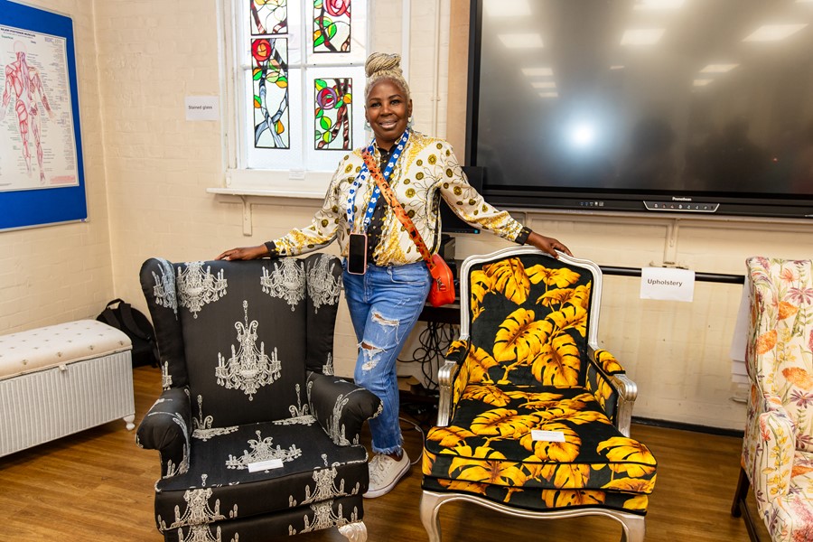 Lady showcasing two chairs she upholstered