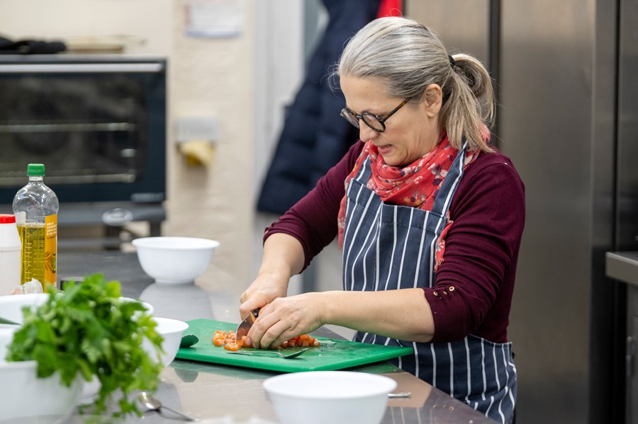 Lady in striped apron chopping vegetables