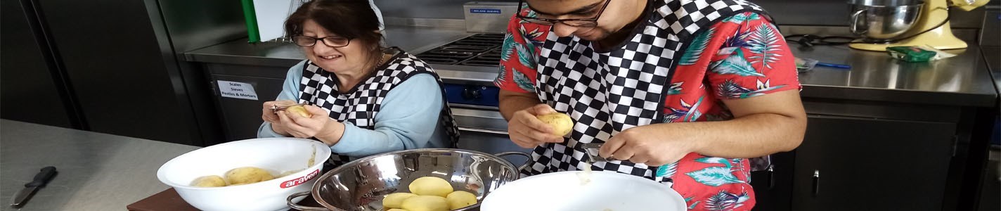 Man and lady in a kitchen peeling potatoes