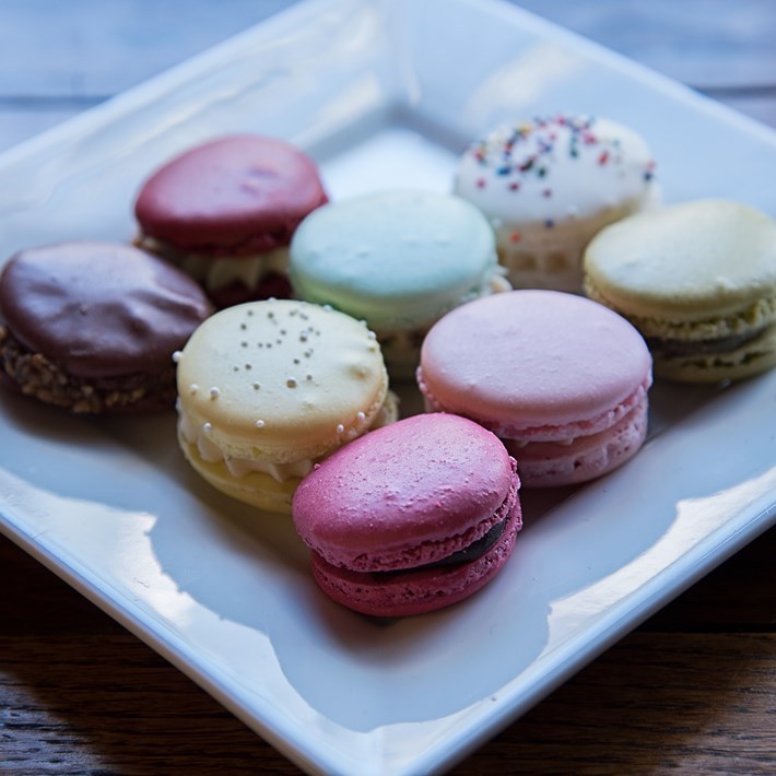 Macarons of different colours on a white square plate