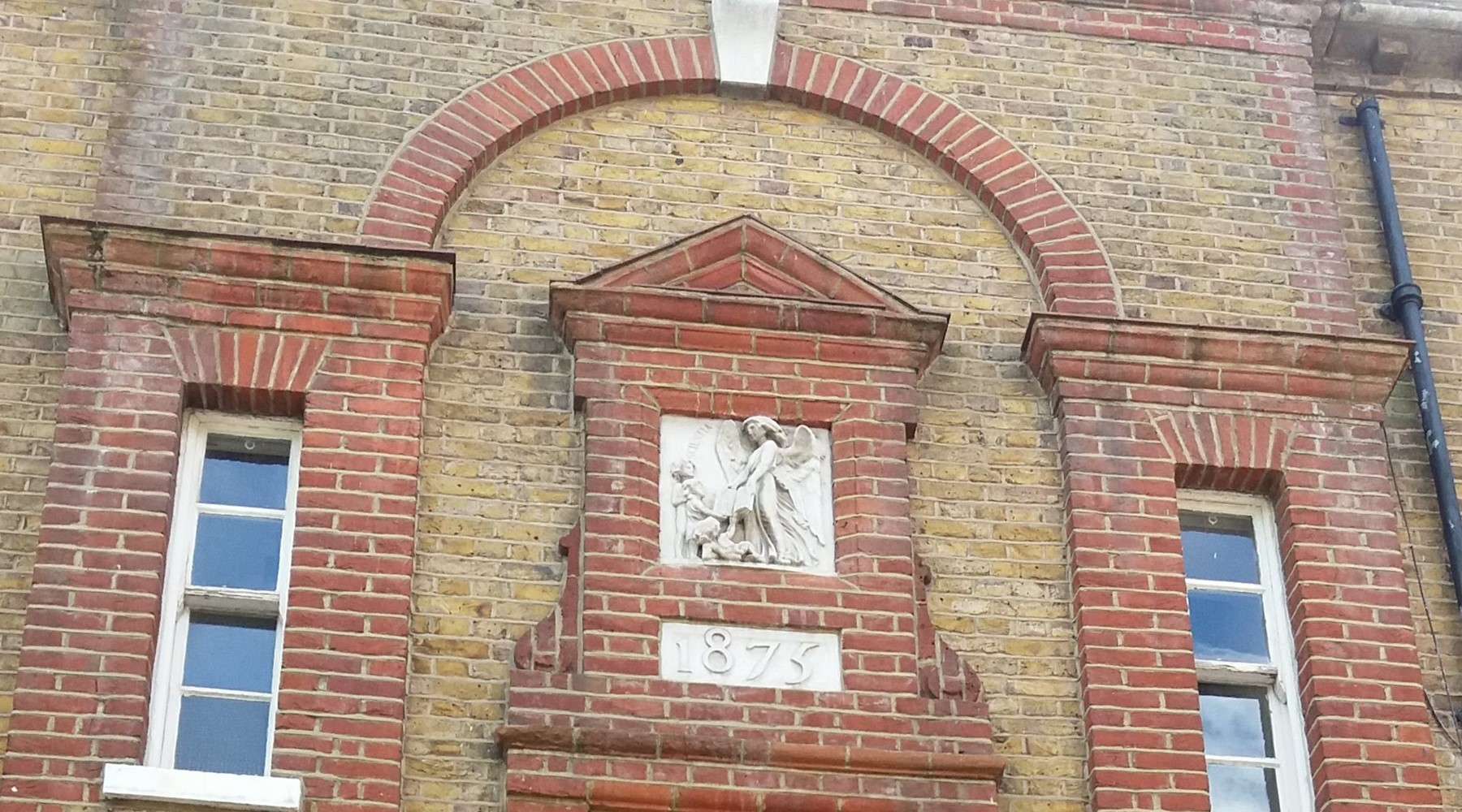 Macbeth façade plaque depicts two children receiving a book from a winged spirit