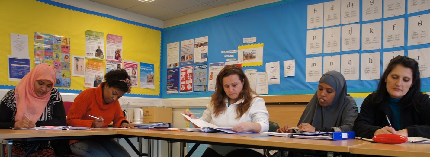 A group of five women sitting at a table in a classroom