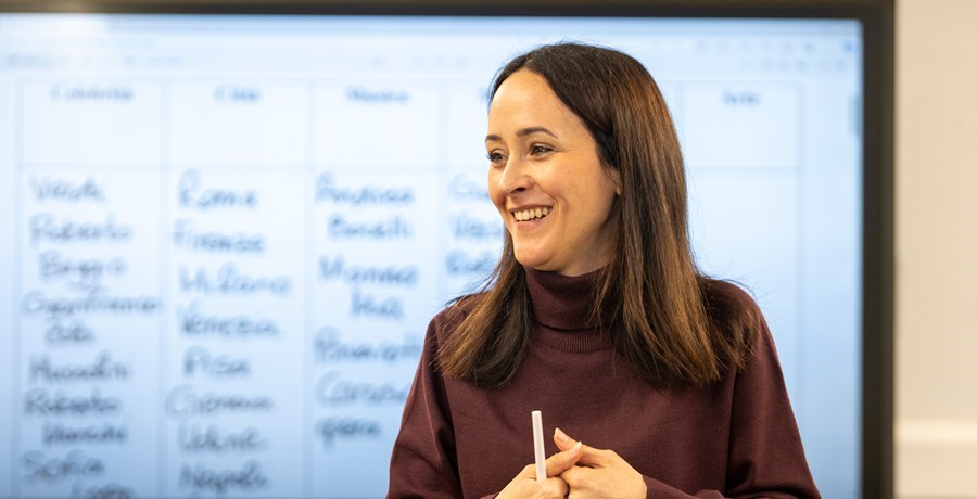 A woman in a brown turtleneck holding a pen