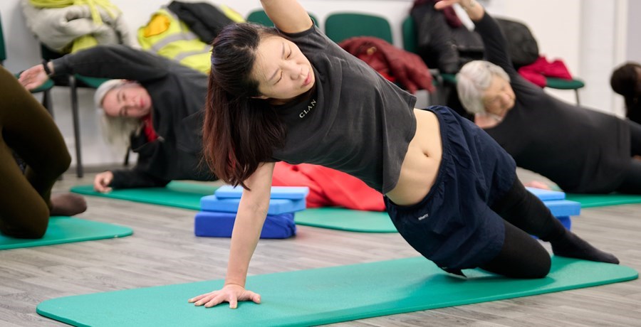 Group of women doing floor exercise on green mats