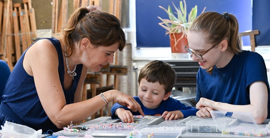 Two women and a young boy doing beading